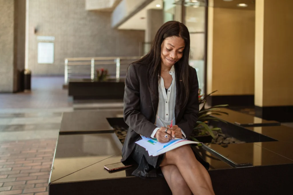 Confident businesswoman reviewing documents while sitting indoors with a smile.