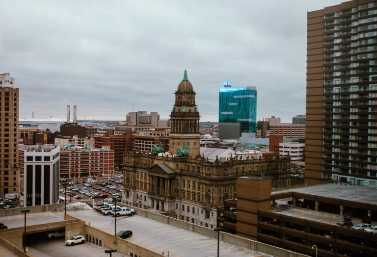 Aerial view of Detroit city showcasing historic and modern buildings under a cloudy sky.