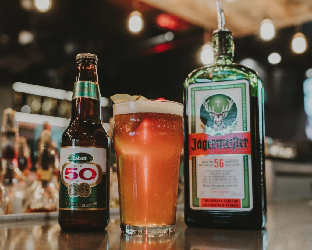 Close-up of Labatt beer, cocktail, and Jägermeister bottle on bar.