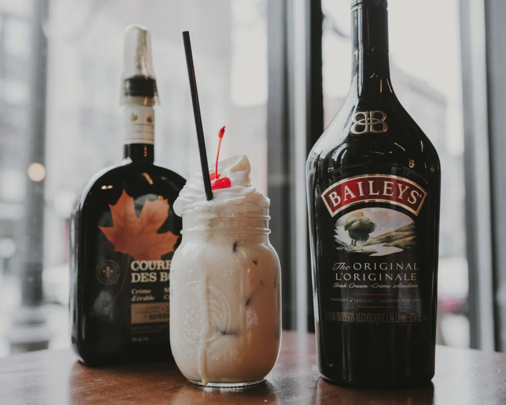 Creamy Baileys cocktail with cherry garnish, captured in a cozy indoor setting. Perfect for dessert drinks.