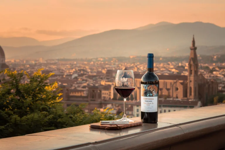 Wine glass and bottle on terrace with Florence skyline at sunset, capturing a tranquil and scenic urban atmosphere.