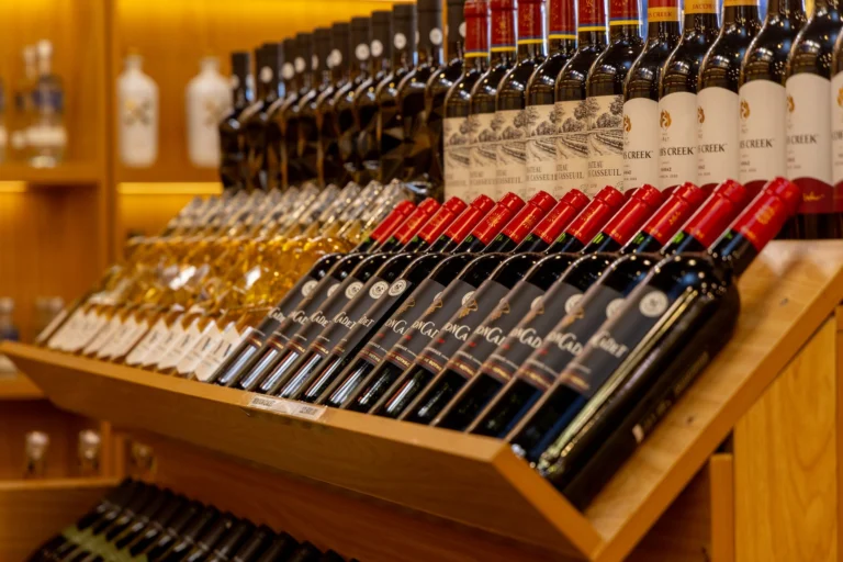 Close-up of diverse wine bottles arranged on a wooden shelf display.