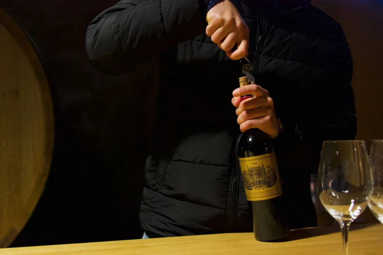 Person uncorking wine bottle in Margaux, Bordeaux. Elegant wine tasting in a French cellar.