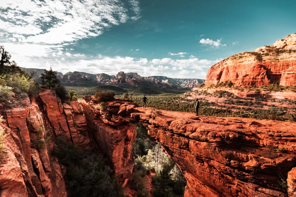 Explorers hiking on Sedona's stunning red rock formations under a vibrant sky.