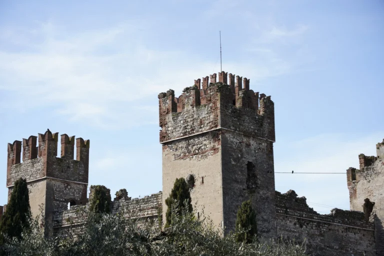 Explore the ancient stone castle towers standing strong against a blue sky in rural Italy.