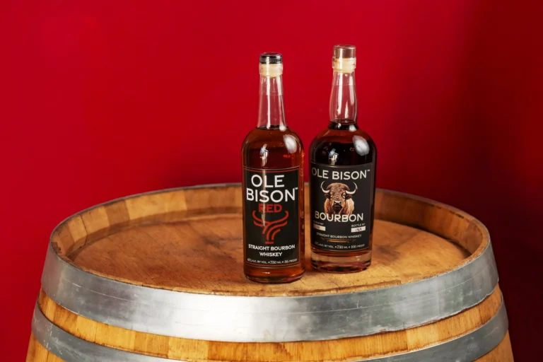 Two Ole Bison bourbon bottles on a barrel against a red background in New Orleans.