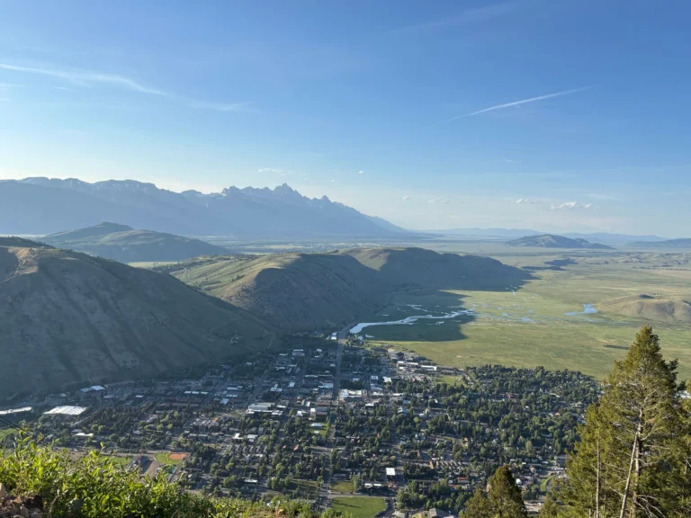 Stunning aerial view of Jackson Hole with the Teton Range in the background under a clear blue sky.