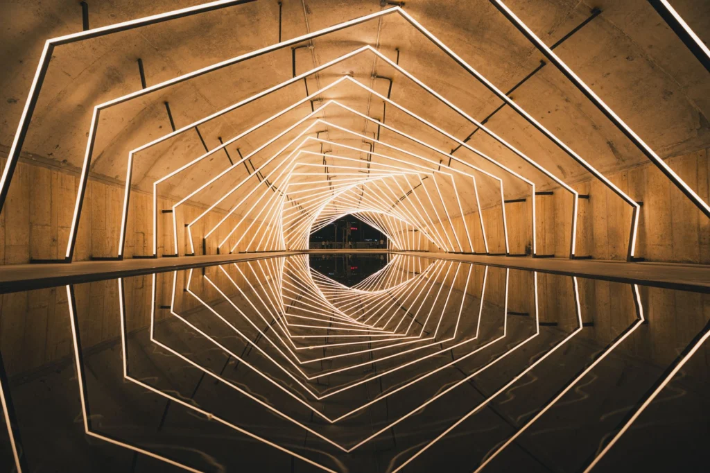 Illuminated geometric tunnel with reflective water surface creating a mesmerizing visual symmetry.