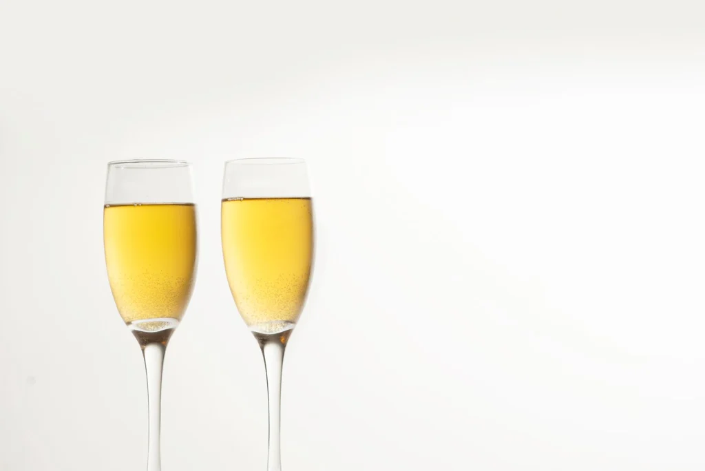 Two champagne glasses filled with bubbly drink on a white background, ideal for celebration themes.