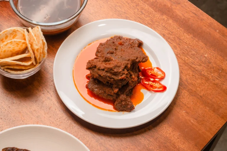 Savor the rich flavors of Nigerian beef stew with fresh tomato slices and traditional flatbread.