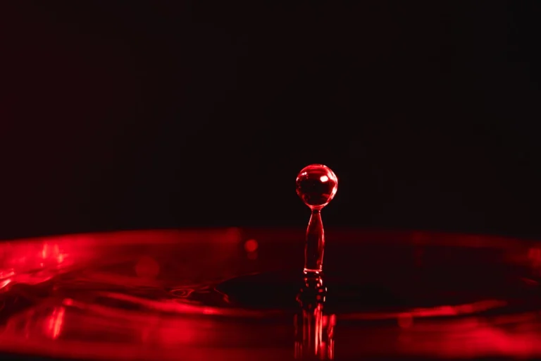 A striking macro photograph of a red water droplet suspended mid-air, showcasing abstract beauty and motion.