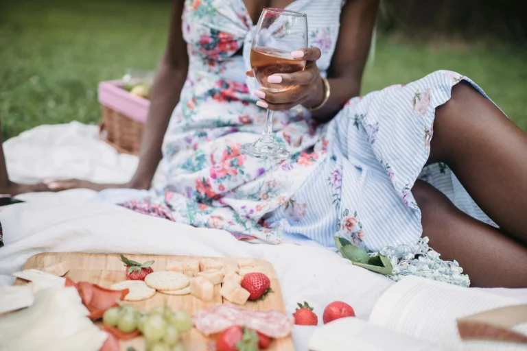 A relaxing outdoor picnic with wine and snacks, featuring fresh fruits and cheese on a sunny day.