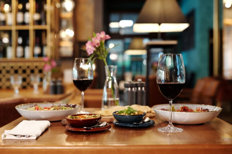 A meticulously arranged restaurant table setting with red wine and various appetizers.