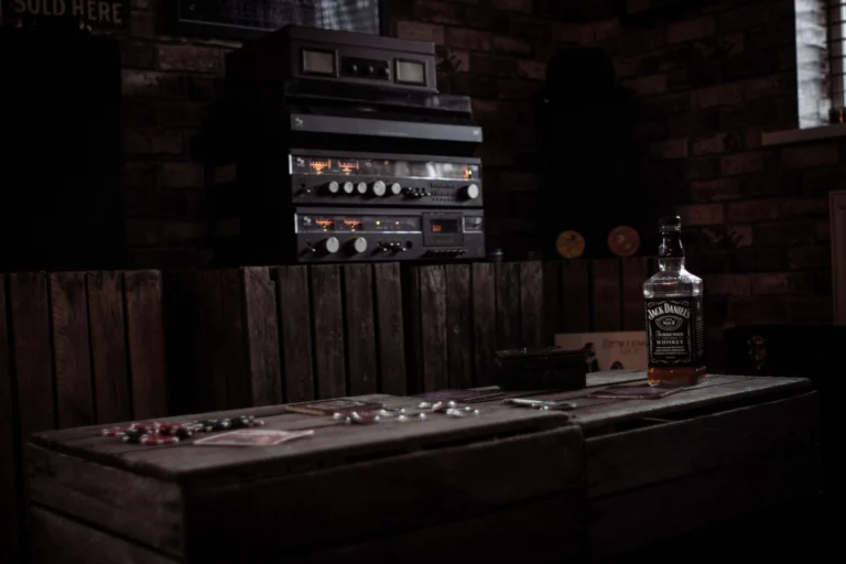 Cozy bar interior with a whiskey bottle on a wooden table and a vintage stereo setup.