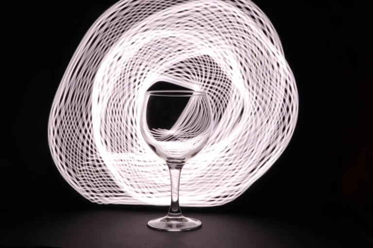 An artistic light painting featuring a wine glass against a spiral pattern background.