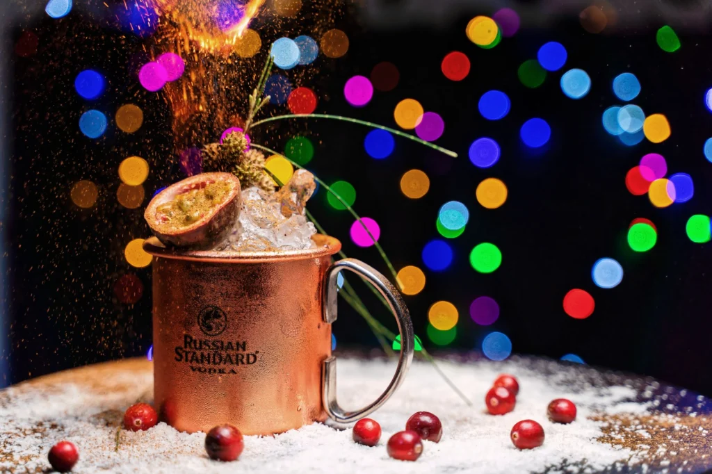 Vibrant cocktail with fruits and bokeh lights in a festive Dubai setting.