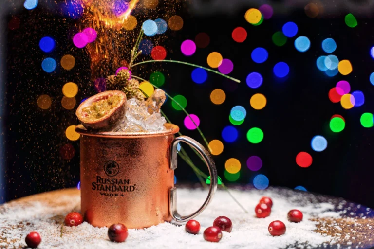 Vibrant cocktail with fruits and bokeh lights in a festive Dubai setting.