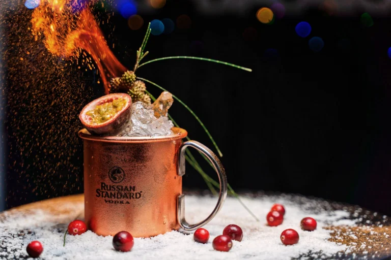 Vibrant drink in a copper mug with fiery garnish, perfect for cocktail lovers.