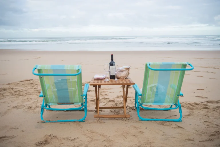 Tranquil beach setup with chairs and wine at Portugal's coast, perfect for relaxation.