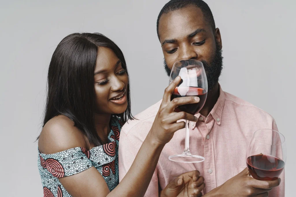 Happy couple sharing a moment while tasting red wine indoors.
