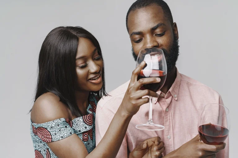 Happy couple sharing a moment while tasting red wine indoors.