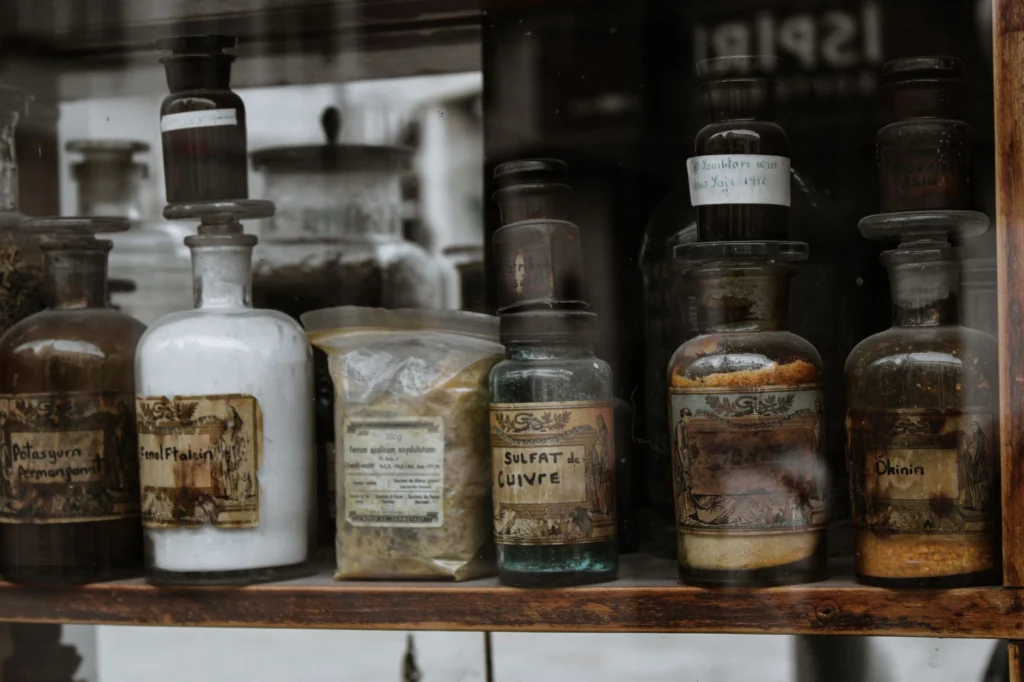 Collection of vintage apothecary bottles with handwritten labels on a wooden shelf, reflecting a medieval charm.