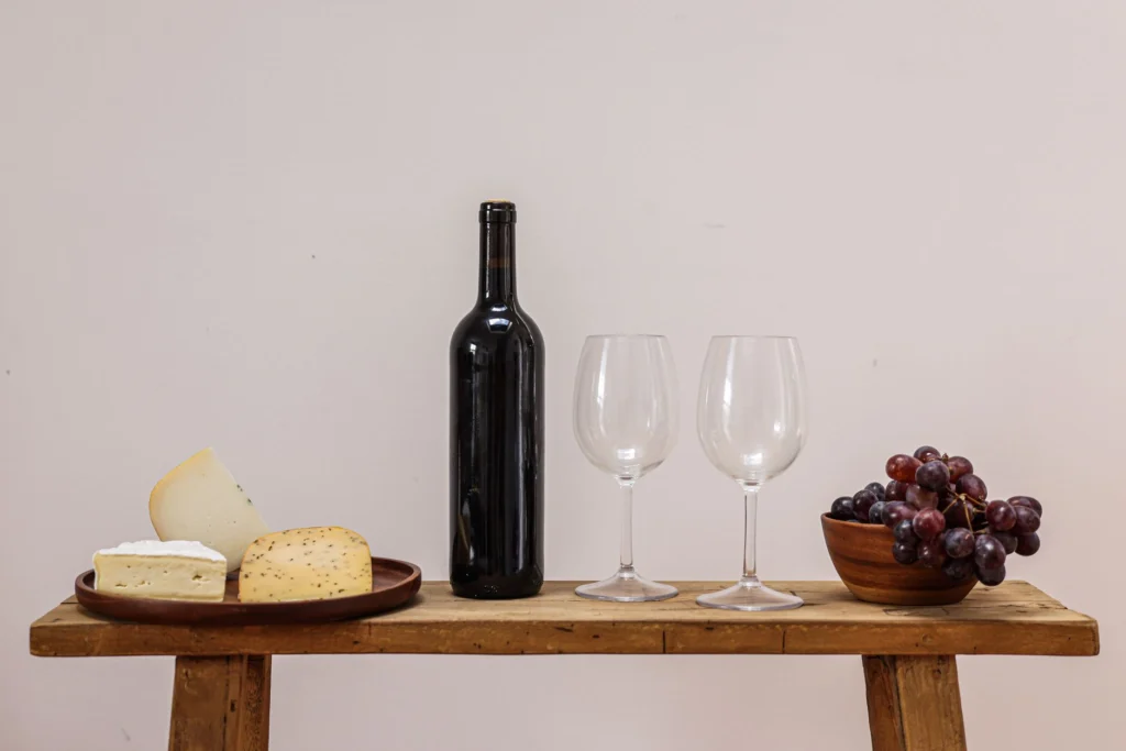 Elegant wine and cheese setup with grapes on a wooden table, perfect for dining scenes.