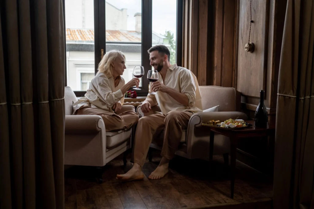 Romantic couple toasting with red wine in an elegant living room, showcasing warmth and love.
