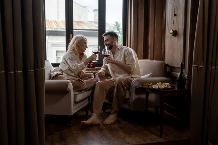 Romantic couple toasting with red wine in an elegant living room, showcasing warmth and love.